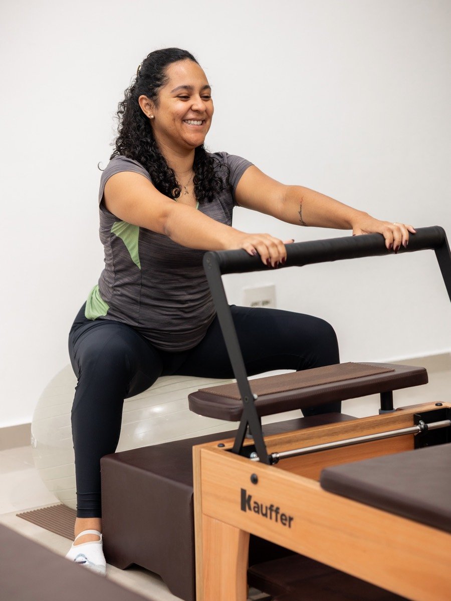 Paciente sorrindo durante exercício com bola suíça e Chair